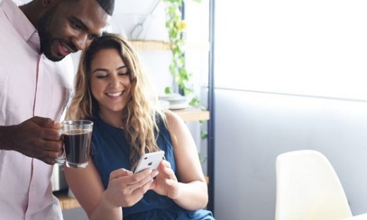 A man holds a cup of coffee and a woman are looking at Lumen's application