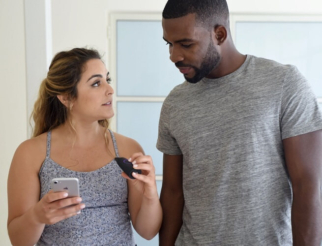 A woman with a Lumen device and a cell phone in her hand looks at a man