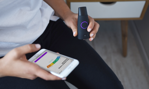 A woman holds Lumen's device and looking at his app